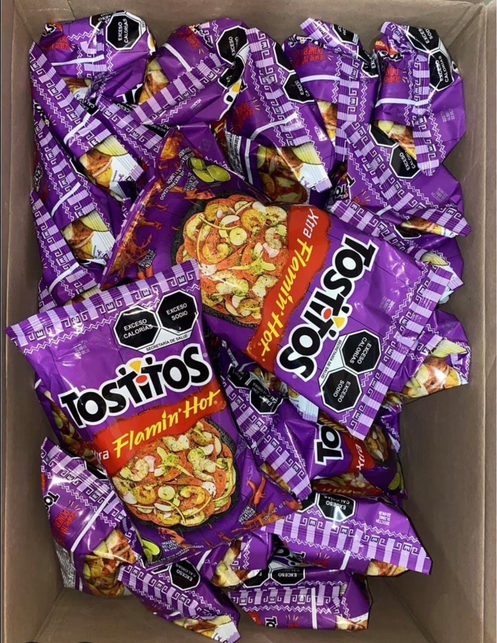 Box full of Tostitos Flamin' Hot chips, each bag showcasing bold graphics and spicy flavor for snacking.