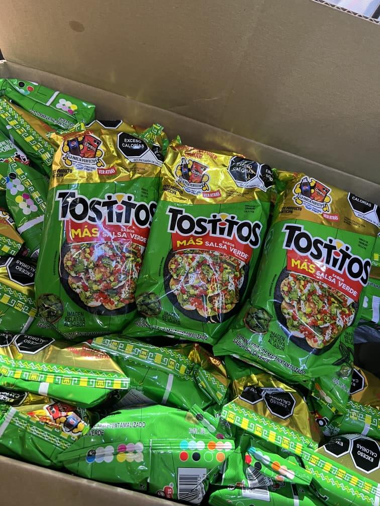 Tostitos Salsa Verde bags stacked in a box, showcasing the vibrant green packaging of spicy tortilla chips.